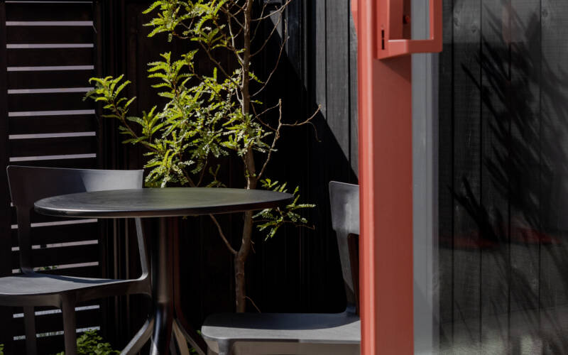 An image from the lounge area of one of the one bedroom self-contained apartments in The Kilmore Collection, Christchurch, showing the outdoor table and two chairs in the enclosed private patio area.